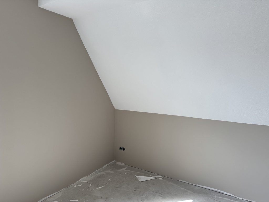 Zolderkamer in een nieuwbouwwoning met een schuine wand, wanden in een warme grijstint en een wit plafond