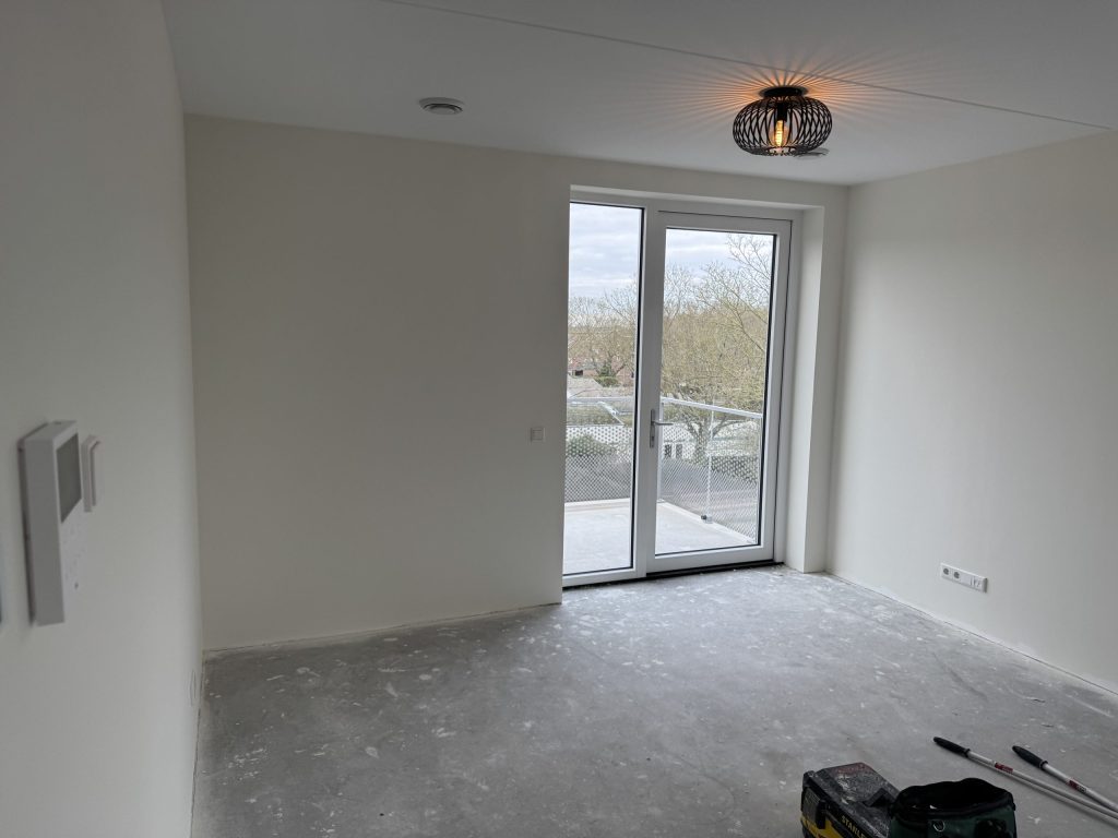 Lege kamer in een nieuw appartement met gladde witte wanden en openslaande deuren naar het balkon